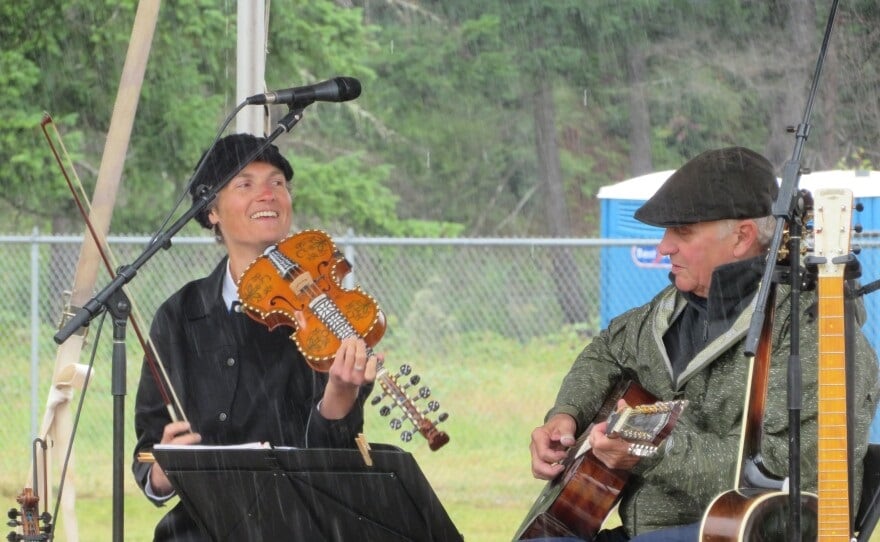 Amey Herman, left, cracks a smile as she and Doug Heydon prepare to play another song at the McKenzie River Solstice Arts Festival. Known as D n A, the duo performed a variety of world music pieces in the cold, wet venue.