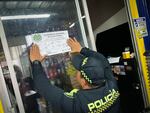 A Bogotá police officer puts up a sign indicating that a tire repair shop has been temporarily shut down due to out-of-date paperwork. Authorities are targeting tire-repair shops that motorists have flagged for their suspected collaboration with pinchallantas, or tire-puncturers.