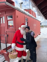 Oregon Field Guide reporter Jule Gilfillan gets a hug from a very real Santa Claus at the Christmas train in Sumpter, Ore.