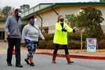An Election Defender volunteer directs voters to an area where they can get free hand sanitizer and masks, during early voting for the Senate runoff election, at a recreation center Thursday, Dec. 17, 2020, in Powder Springs, Ga.