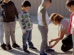 Kindergarten teacher Lupe Fuentes kneels down to tie a student’s shoe.