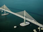 An aerial photo of the Sunshine Skyway Bridge over Tampa Bay in Florida shows both artificial islands surrounding pylons and circular concrete dolphins used as protection against collisions with large vessels.