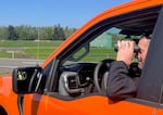 Nick Atwell uses binoculars out of bright orange truck