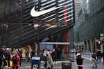 Several people walk by a Nike store with a glass facade on Fifth Avenue in New York City on April 3, 2025.