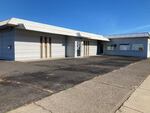 A small, pale blue building sits empty in front of small parking lot