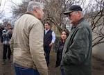 Jeff Merkley speaks with two people in front of a small crowd of people.