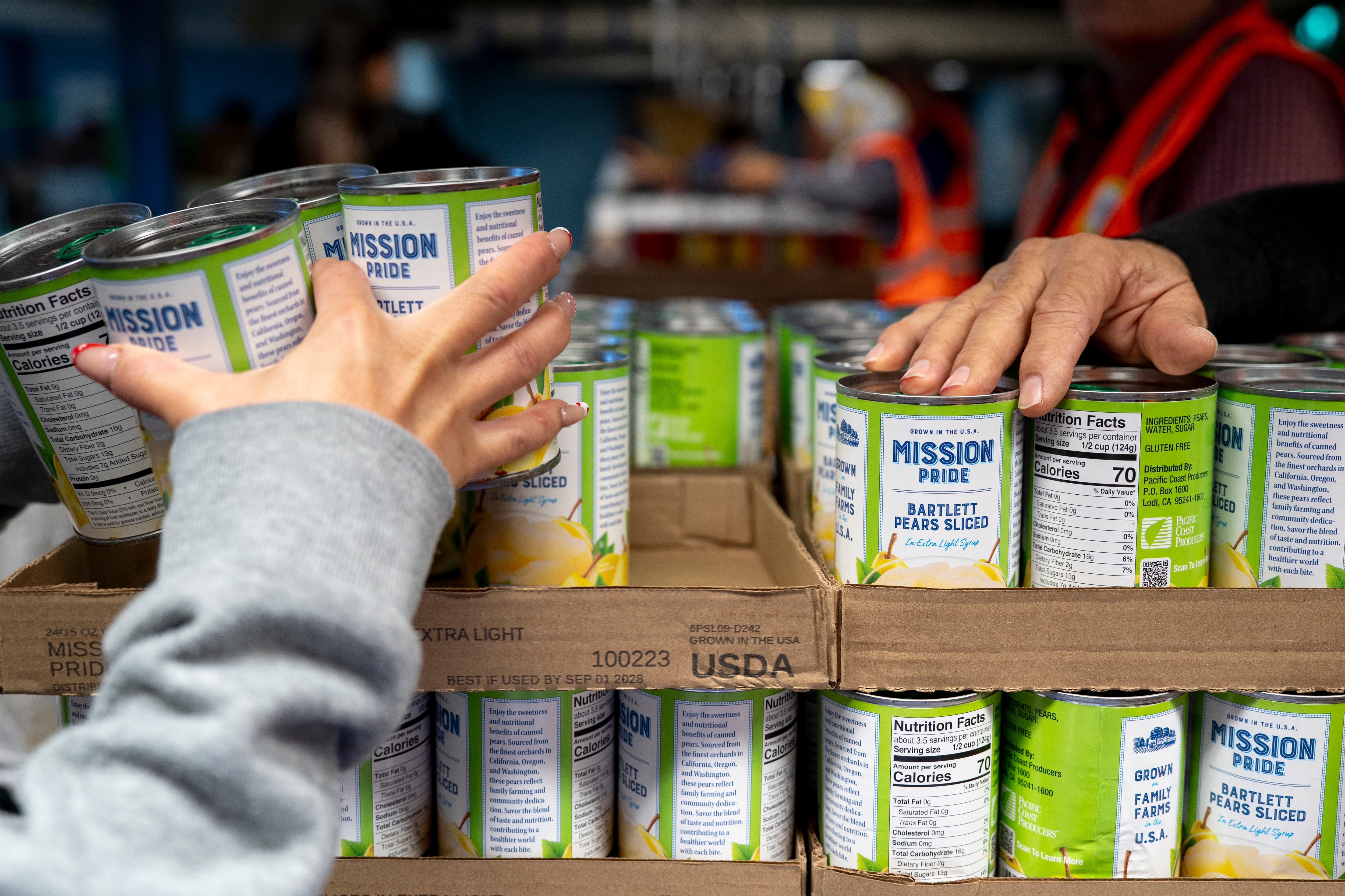 A person gets canned pears from the Ecumenical Ministries of Oregon’s Northeast Emergency Food Program food bank in Portland, Ore., on Tuesday, Oct. 21, 2025.