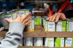 A person gets canned pears from the Ecumenical Ministries of Oregon’s Northeast Emergency Food Program food bank in Portland, Ore., on Tuesday, Oct. 21, 2025.