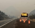 A traffic sign reads "highway closed" next to a smoky stretch of road.
