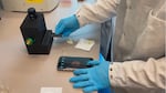 In this video still, a researcher photographs water using a new microplastics detection device developed at the University of British Columbia.