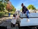 Jaime Smith (right) and her friend Gopher attempt to secure the top of her tent trailer on Clackamas Road on Sept. 30. 2024. Smith says she's been on a waiting list for housing for years.