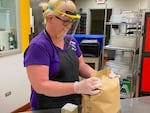 In the Baker School District, a food service employee prepares meals for students. All school staff will wear these face shields, created by Baker Technical Institute Students, for school programming this summer.