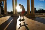 A man rides his skateboard at a park pavilion on a sunny day.
