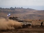 An Israeli soldier runs in front of a tank with an Israeli flag on the top in a staging area near the Israeli border with Lebanon, on Sunday, Oct. 15, 2023.