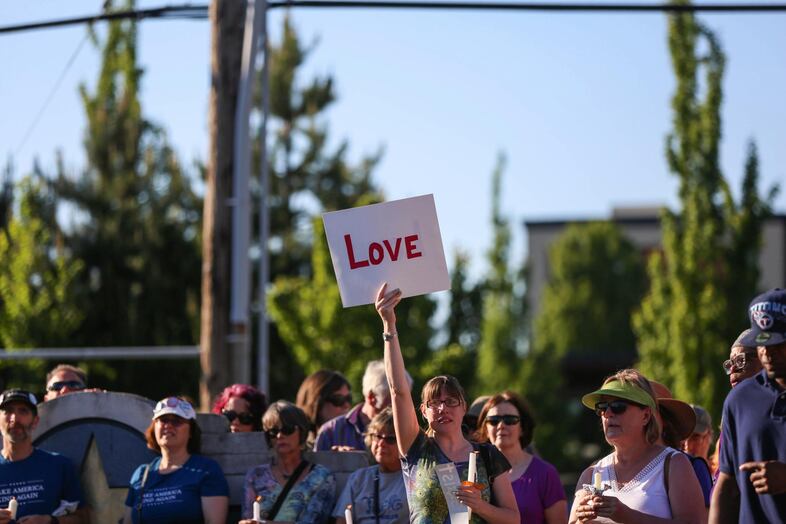 A woman holds a sign that says "LOVE" at a vigil for the MAX attack victims.