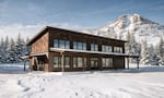 A computer-generated image of a two story wooden building with a snow-capped mountain in the background.