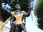 A statue of Sir Laurence Olivier in London with a baby carrier attached to his chest.