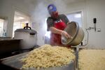 Dominique Cataldi, kitchen and staff assistant at Loaves & Fishes of Tompkins County, prepares rice for a meal on Monday, Dec. 7, 2020, in Ithaca, N.Y. In Ithaca, N.Y. In Ithaca, advocates have expanded outreach to encampments and other places where people are sheltering. Christian ministry Loaves & Fishes boxes up about 250 lunches or dinners a day for delivery around the area.