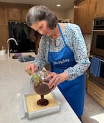 Blue Sky Baking owner Rachel Rencher pours chocolate ganache onto custard filling inside the Nanaimo bar pan at her home in Portland, Ore., on May 28, 2026.
