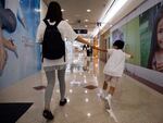 Pamela Lam plays with her son on the way to school in Hong Kong, July 3, 2020. Lam's 6-year-old son fell in love with the Hong Kong protest anthem, Glory to Hong Kong, the first time he heard it and sings it often. But because of a sweeping new national security law, singing it in public is now risky. Lam agreed to be photographed only if her face was not shown, fearing possible retribution from authorities. 