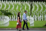 FILE - A man and woman walks past rows of crosses after a ceremony to mark U.S. Veterans Day at the Manila American Cemetery and Memorial in metropolitan Manila, Philippines on Friday, Nov. 11, 2022. Remains of World War II veteran U.S. Army Pvt. William E. Calkins, from Oregon's Washington County, were recently identified from those of unknown soldiers buried at the cemetery.