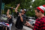 A man identifying as Tango Down speaks into the loudspeaker outside Portland City Hall in protest of public funds going to the Moda Center.