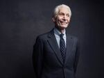 A man in a suit and tie smiles in a professional-style photo portrait.