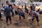 Palestinians dig through sand looking for belongings after an Israeli strike hit a displacement tent camp in Gaza City, Saturday.