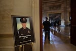A placard on a stand shows an image of a Capitol police officer with the text "Officer Brian Sicknick, 1978-2021."