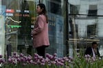 People stand outside a brokerage house where an electronic board displays shares trading.