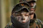 Two German recruits, wearing camouflage face paint and camouflage-print uniforms, attend a tank destruction exercise at the Westfalen-Kaserne barracks of the German armed forces on November 13, 2025. They are photographed from about the shoulders up.