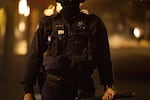 A close up of a  police officer shows their uniform from waste to neck, with their legs and  head cropped out of the image. A sticker covers the area where a name tag might appear.