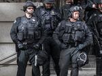 Police officers in military-like black attire stand shoulder to shoulder.