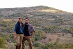 Siblings Marie-Charlotte Piro and Romain Piro stand among some of the olive trees they harvest in Tuscany, Italy, to create their olive oil.