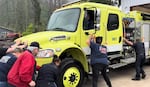 As part of a grand opening celebration, fire fighters with the Upper McKenzie Rural Fire Protection Department push their engine into the new fire station in Blue River, Ore.