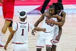 Illinois guard Da'Monte Williams (20) is hugged from behind by guard Ayo Dosunmu (11) and they celebrate with Illinois guard Trent Frazier (1) on a basketball court.