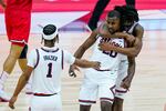 Illinois guard Da'Monte Williams (20) is hugged from behind by guard Ayo Dosunmu (11) and they celebrate with Illinois guard Trent Frazier (1) on a basketball court.