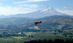A vintage biplane from WAAAM's collection flies over the farmlands of Hood River.