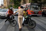 A traffic police official stops motorcyclists whose back passengers are not wearing helmets, in Mumbai, India, on June 9, 2022.