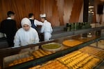 Baklava bakers and servers stand behind a large glass case of baklava at Kocak, a glitzy tourist hotspot in Gaziantep.