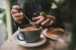 Close up of hands and cup, making tea in morning light, having breakfast in a cafe