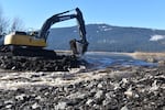 An excavator operator works on a bed of soil and rip-rap as water pours from Agency Lake into a newly-flooded area of the Upper Klamath Wildlife Refuge in part of the largest freshwater habitat restoration project in the Western U.S.