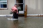 A man carries belongings through floodwaters from a home in Bridgewater, Vt., on Monday, July 10.