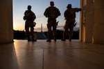 The Washington Monument is seen in the distance as members of the National Guard stand atop the steps at the Lincoln Memorial at sunrise on the National Mall in Washington, DC, on July 23, 2026.