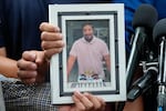 Ronaldo Salgado and Lorenzo Jr., sons of Lorenzo Salgado Araujo, hold a photograph of their father during a news conference Wednesday, July 8, 2026, in Houston.