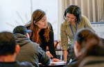 Mariela de Jesus, left, and Lucinda Law help asylum seekers fill out paperwork.