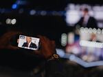 A crowd member uses his phone to record Republican presidential candidate Donald Trump speaking on the final night of the 2024 Republican National Convention. 