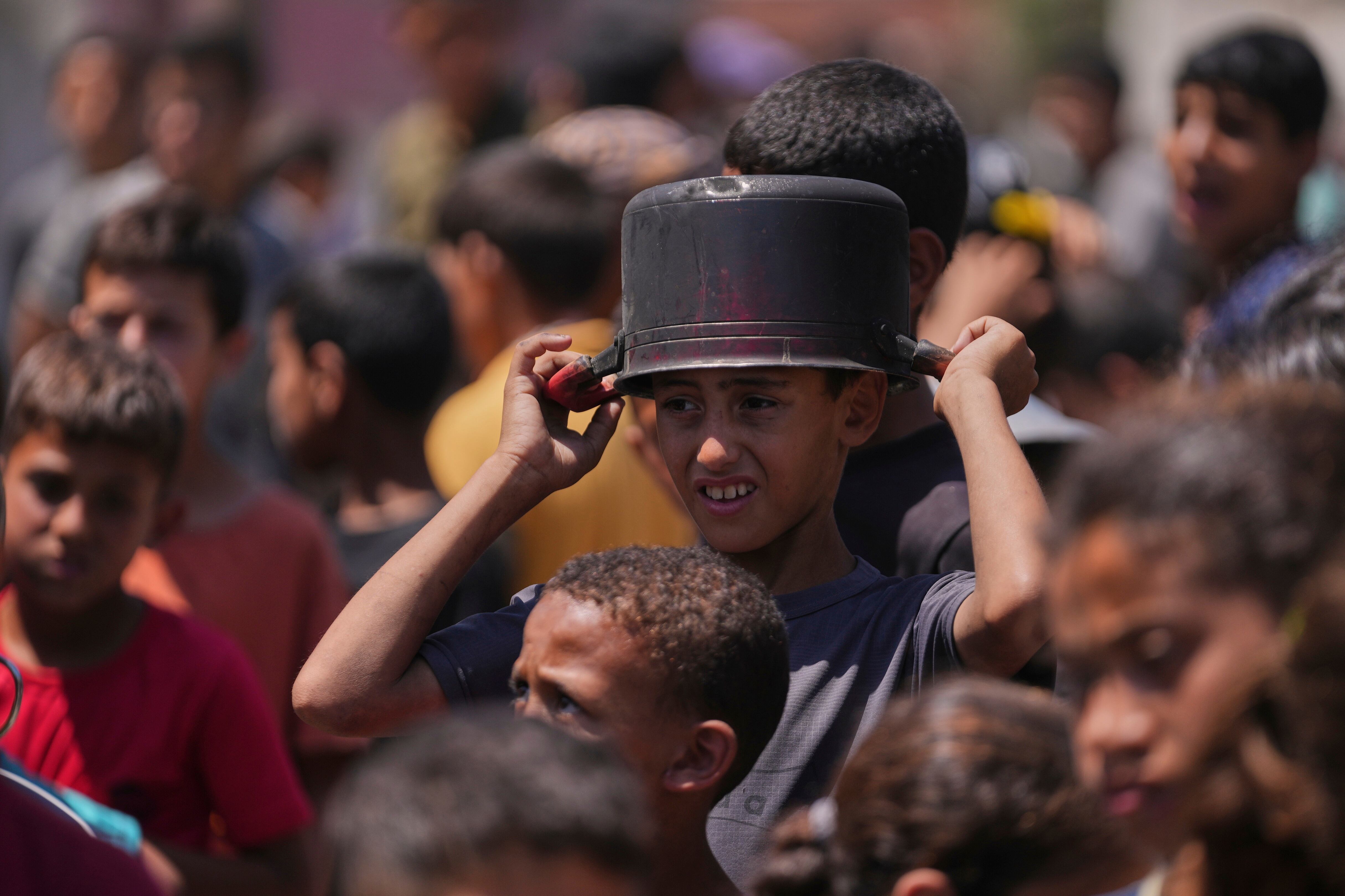A young Palestinian waits to collect donated food at a food distribution kitchen in Deir al-Balah, Gaza Strip, Friday, May 30, 2025.