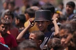 A young Palestinian waits to collect donated food at a food distribution kitchen in Deir al-Balah, Gaza Strip, Friday, May 30, 2025.