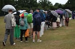 Spectators queue under umbrellas as it rains on day three at Wimbledon, July 2.